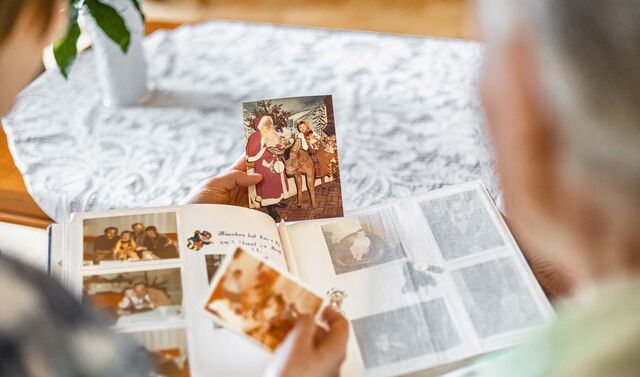 Zwei Personen schauen sich Fotos an und blättern durch ein Fotoalbum.